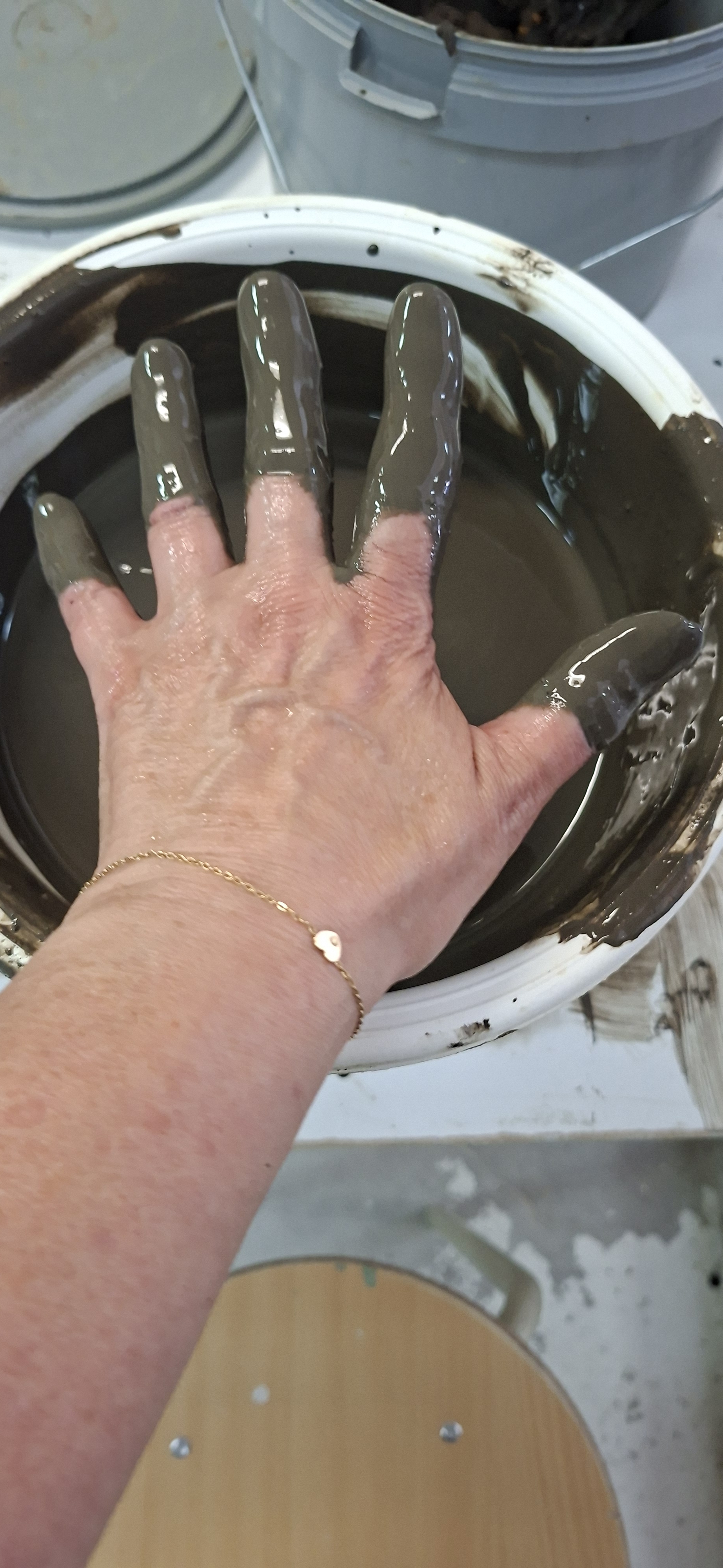 Hand strijkt de binnenkant van een keramische schaal glad in het atelier