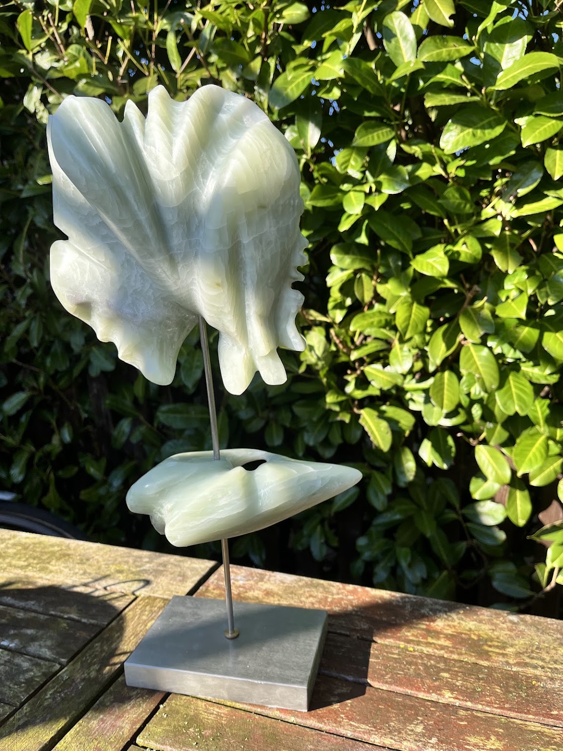 Wit keramisch beeld op een sokkel in de tuin bij de studio
